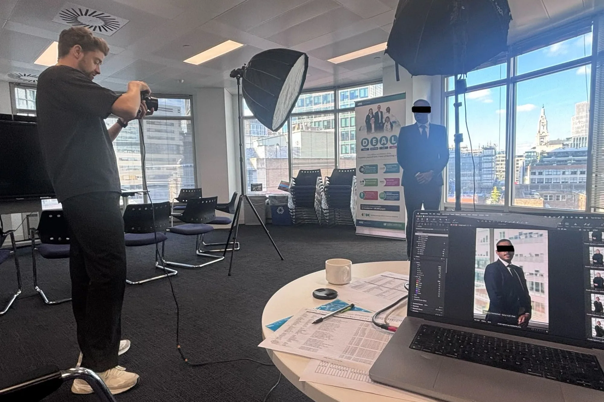 Le photographe Etienne Morax réalisant un portrait de collaborateur dans les bureaux londoniens de Crédit Agricole CIB, avec deux boîtes à lumière, la City en fond et un ordinateur relié à l'appareil affichant le portrait