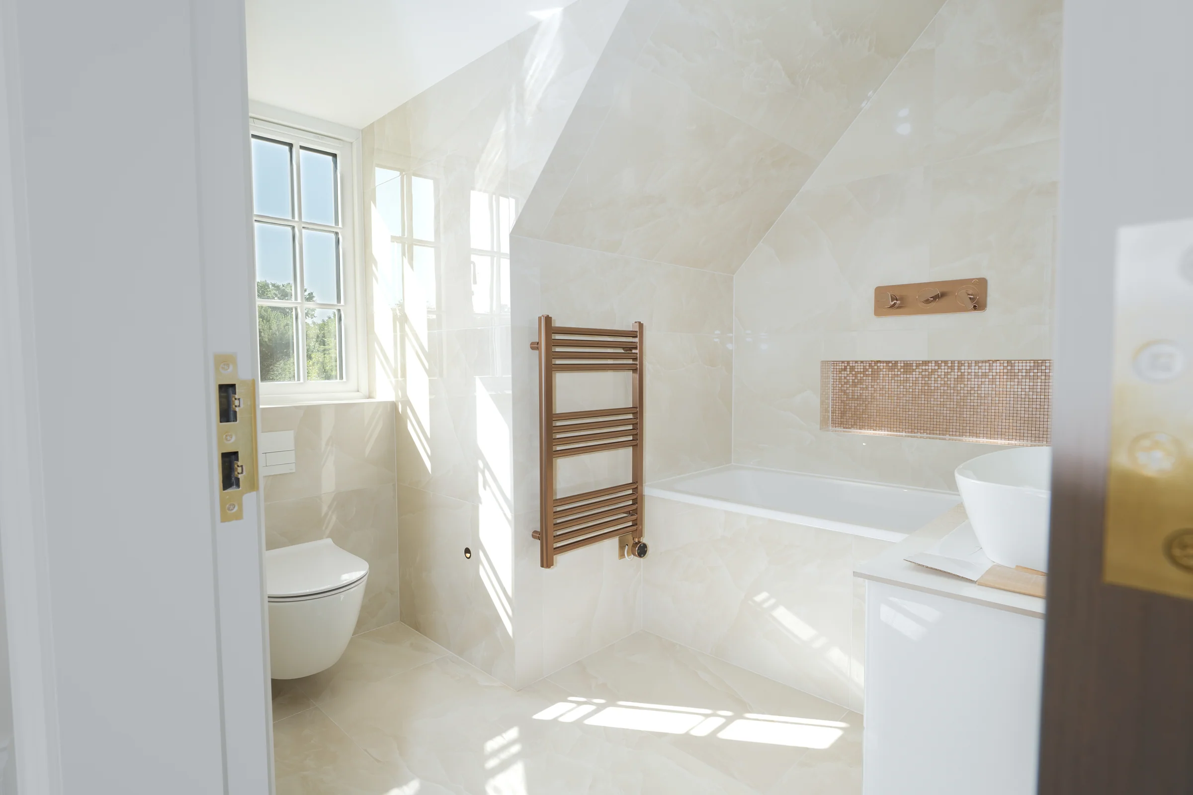 Salle de bains habillée d'onyx avec baignoire, sèche-serviettes en laiton et lumière du matin, dans une villa de Finchley en travaux